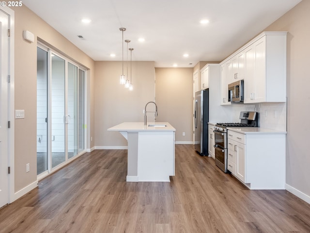 kitchen featuring appliances with stainless steel finishes, a sink, light countertops, light wood-style flooring, and recessed lighting