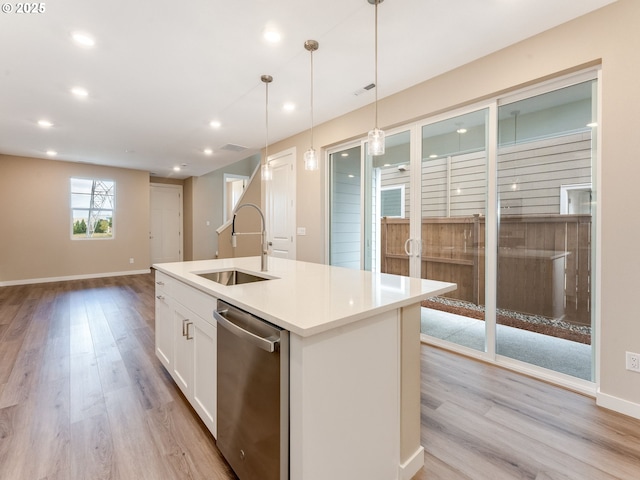 kitchen featuring stainless steel dishwasher, a sink, light wood-style flooring, white cabinets, and decorative light fixtures