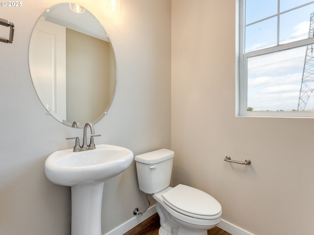 bathroom featuring baseboards, plenty of natural light, toilet, and wood finished floors