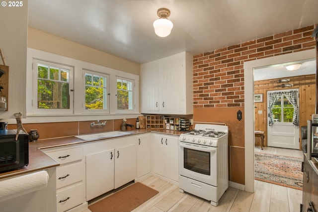 26630 E Roberts Rd, Welches, OR 97067 - kitchen with white gas range, stainless steel countertops, a sink, white cabinetry, and light wood-style floors