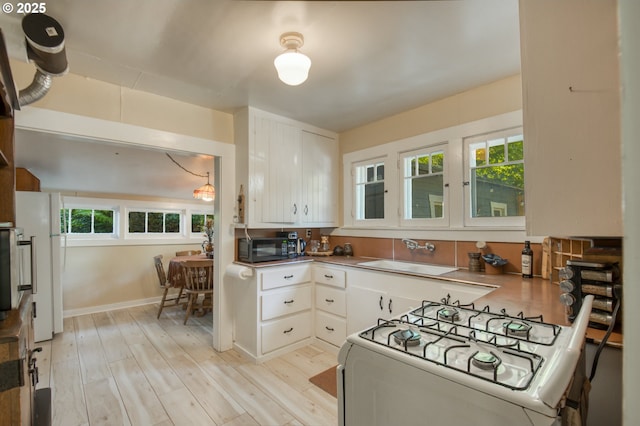 26630 E Roberts Rd, Welches, OR 97067 - kitchen featuring white range with gas stovetop, stainless steel countertops, a sink, white cabinetry, and black microwave