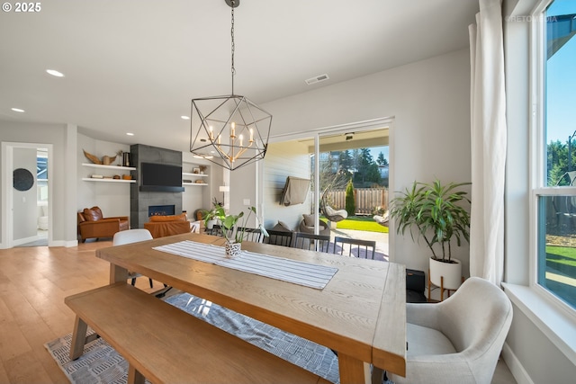 dining area with a chandelier, a tile fireplace, and light hardwood / wood-style floors