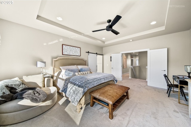 bedroom featuring a barn door, ceiling fan, a raised ceiling, and light colored carpet