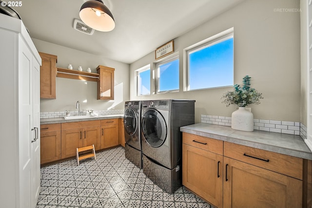 clothes washing area featuring sink, cabinets, and washer and clothes dryer