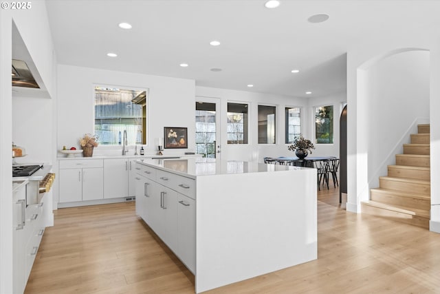 kitchen with sink, a center island, light hardwood / wood-style floors, and white cabinets