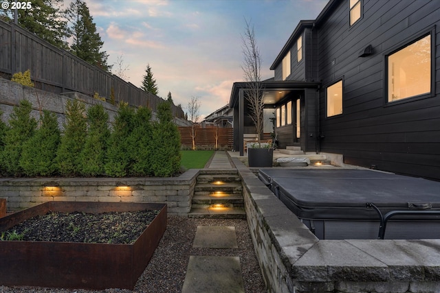 patio terrace at dusk featuring a hot tub