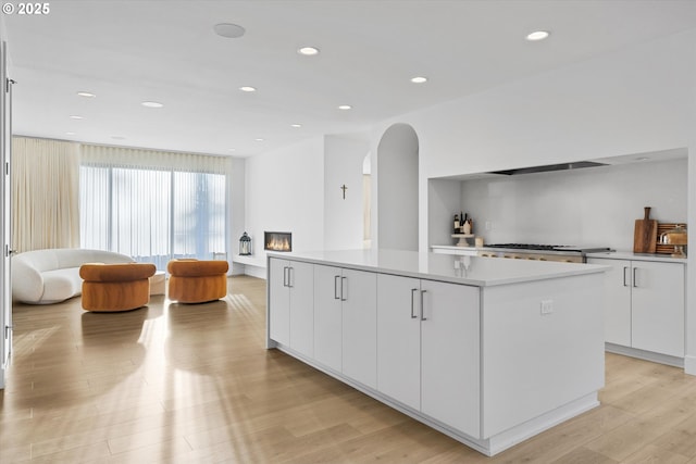 kitchen featuring stainless steel gas stovetop, a center island, white cabinets, and light wood-type flooring