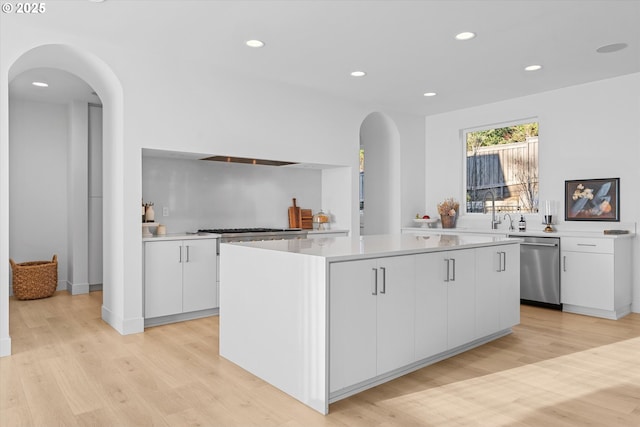 kitchen featuring light hardwood / wood-style flooring, a center island, white cabinets, and appliances with stainless steel finishes