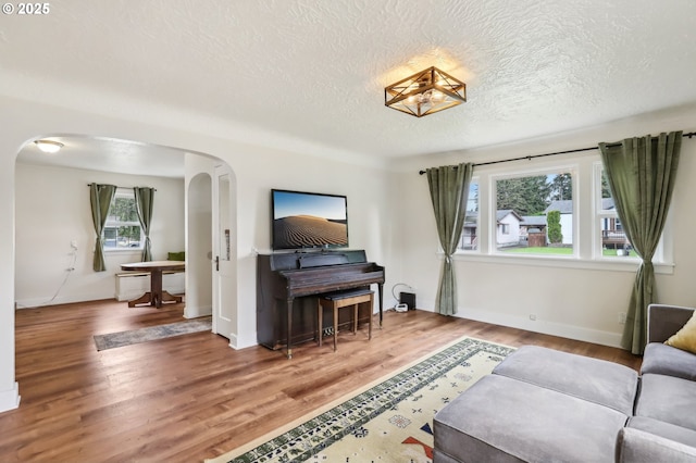 545 N St, Castle Rock, WA 98611 - living area featuring arched walkways, a textured ceiling, healthy amount of natural light, and wood finished floors