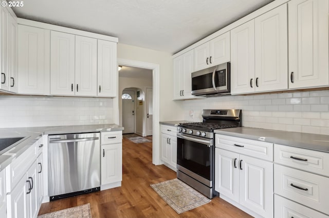545 N St, Castle Rock, WA 98611 - kitchen featuring stainless steel appliances, arched walkways, white cabinets, and backsplash