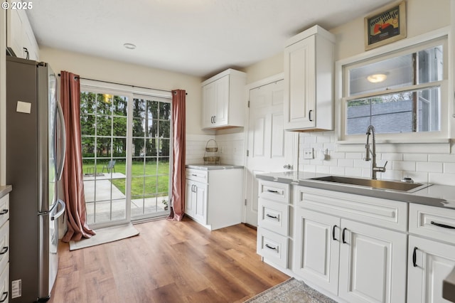 545 N St, Castle Rock, WA 98611 - kitchen with freestanding refrigerator, a sink, decorative backsplash, white cabinetry, and light wood-style floors
