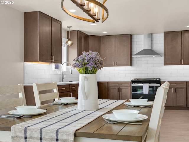 35692 Bella Ridge Loop, Astoria, OR 97103 - kitchen featuring backsplash, pendant lighting, black range with electric cooktop, wall chimney range hood, and light wood-style floors