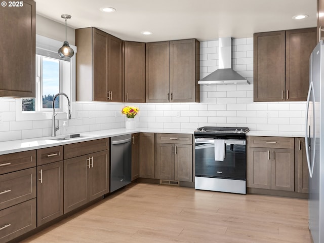 35692 Bella Ridge Loop, Astoria, OR 97103 - kitchen with light wood-style flooring, stainless steel appliances, wall chimney exhaust hood, a sink, and backsplash