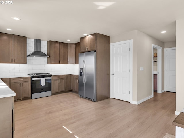 35692 Bella Ridge Loop, Astoria, OR 97103 - kitchen with wall chimney exhaust hood, appliances with stainless steel finishes, light wood-type flooring, baseboards, and decorative backsplash