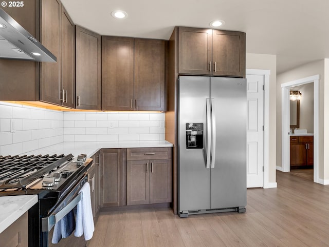 35692 Bella Ridge Loop, Astoria, OR 97103 - kitchen with recessed lighting, stainless steel appliances, range hood, decorative backsplash, and light wood-style flooring