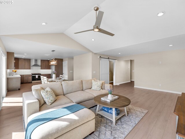 35692 Bella Ridge Loop, Astoria, OR 97103 - living room with lofted ceiling, baseboards, a barn door, ceiling fan, and light wood-style flooring