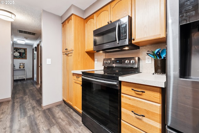 8312 SW Tygh Loop, Tualatin, OR 97062 - kitchen with black range with electric cooktop, freestanding refrigerator, dark wood-style flooring, light countertops, and tasteful backsplash