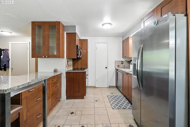 1481 SW 5th Pl, Gresham, OR 97080 - kitchen featuring stainless steel appliances, brown cabinets, glass insert cabinets, light tile patterned floors, and light stone counters