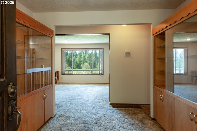 corridor with baseboards and light colored carpet