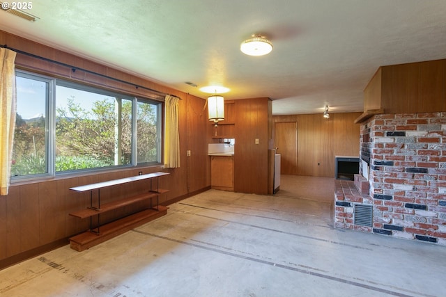 interior space with concrete flooring, visible vents, and wooden walls