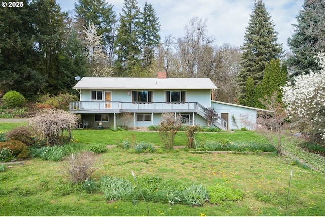 back of house featuring a chimney, a wooden deck, stairs, and a lawn