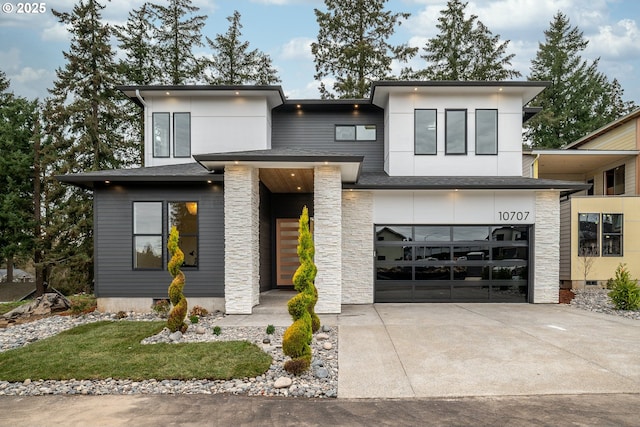 contemporary home featuring stone siding, a garage, and driveway