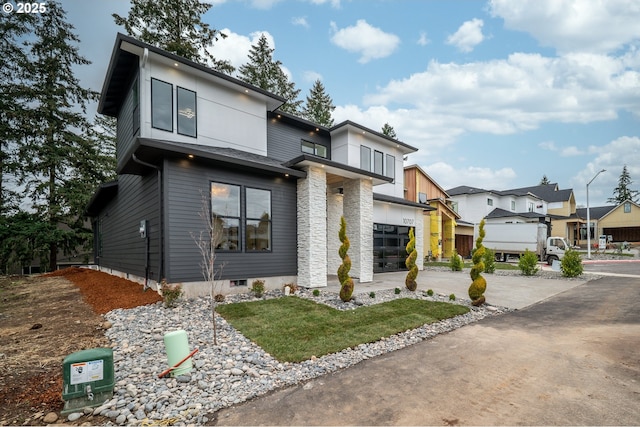 contemporary home with stone siding, concrete driveway, a balcony, and a residential view