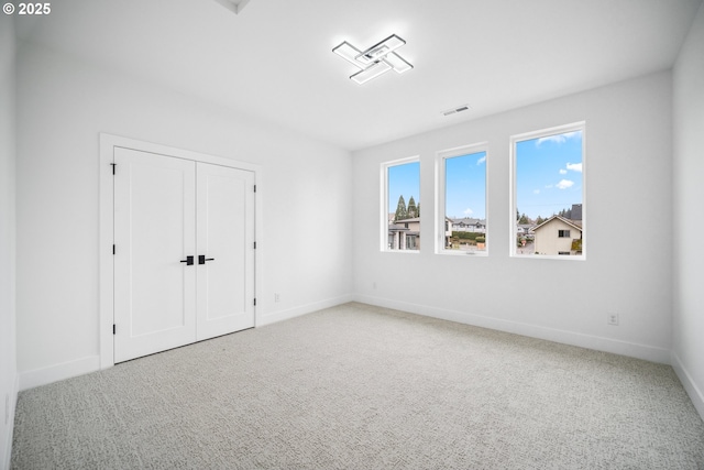 unfurnished room with carpet flooring, baseboards, and visible vents