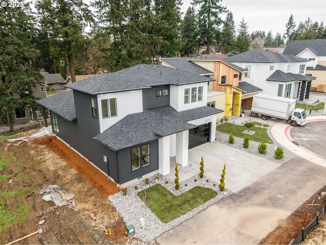 view of front facade featuring a garage, a residential view, driveway, and roof with shingles