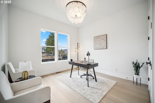 office area with light wood finished floors, visible vents, and baseboards