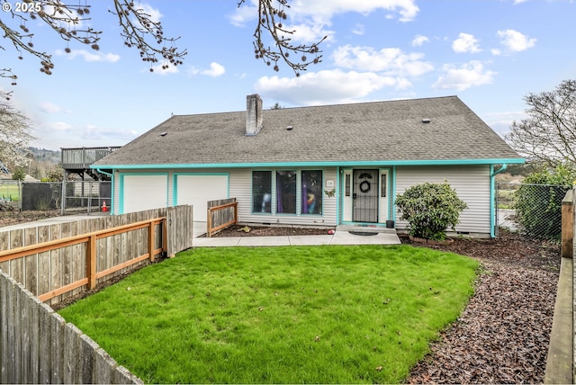 rear view of house featuring an attached garage, a yard, a shingled roof, and fence