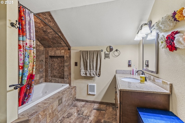 bathroom featuring vanity, baseboards, a textured wall, a textured ceiling, and tiled shower / bath combo