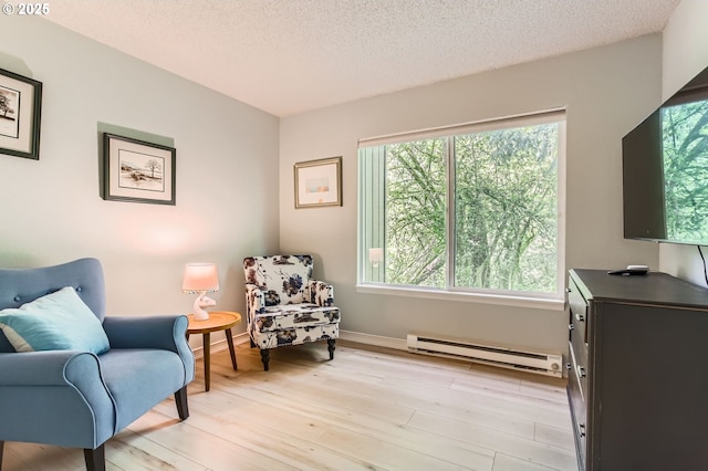 sitting room featuring light wood-style floors, a textured ceiling, baseboards, and baseboard heating