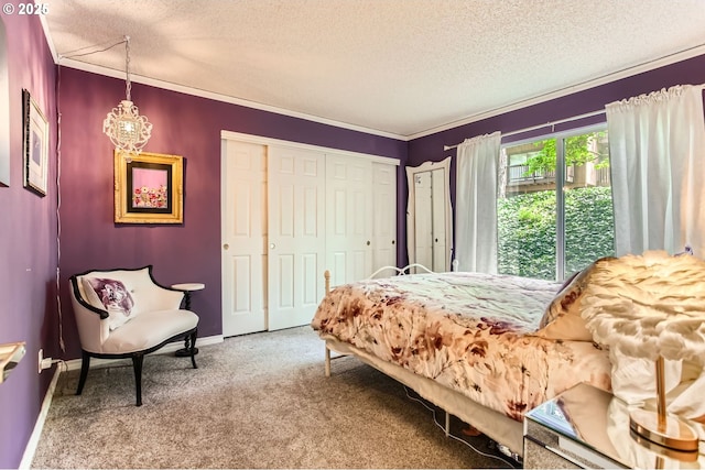 carpeted bedroom with an inviting chandelier, a textured ceiling, baseboards, and a closet