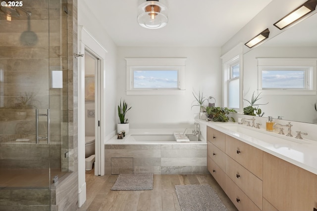 full bathroom with vanity, shower with separate bathtub, hardwood / wood-style floors, and toilet