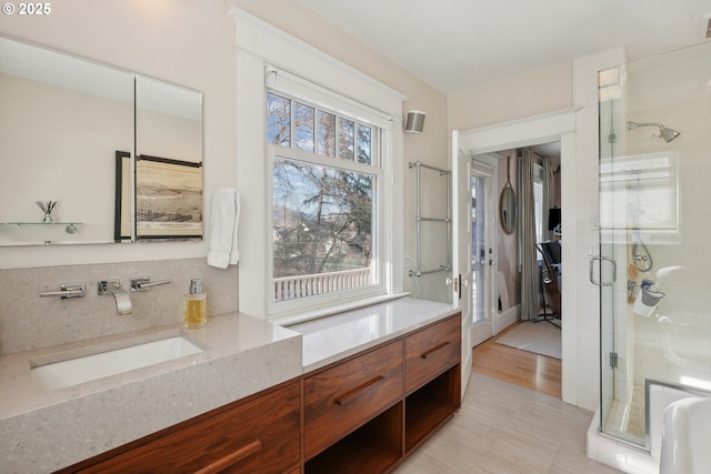 bathroom with vanity, a shower with shower door, and backsplash