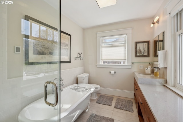 bathroom featuring tile walls, vanity, a bath, tile patterned floors, and toilet