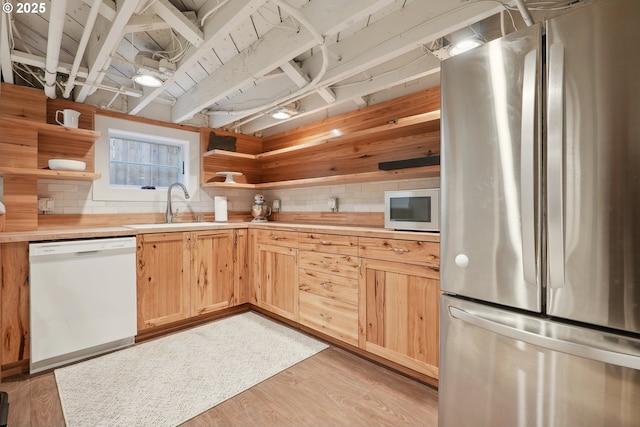 kitchen with stainless steel refrigerator, dishwasher, sink, decorative backsplash, and light wood-type flooring