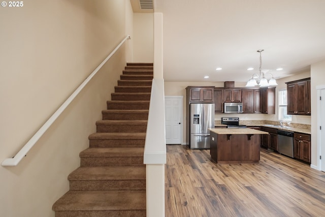 14146 Brittany Ter, Oregon City, OR 97045 - kitchen with appliances with stainless steel finishes, a sink, dark brown cabinets, a chandelier, and a center island
