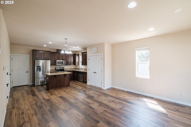 14146 Brittany Ter, Oregon City, OR 97045 - kitchen featuring stainless steel appliances, a chandelier, a kitchen island, dark brown cabinets, and baseboards