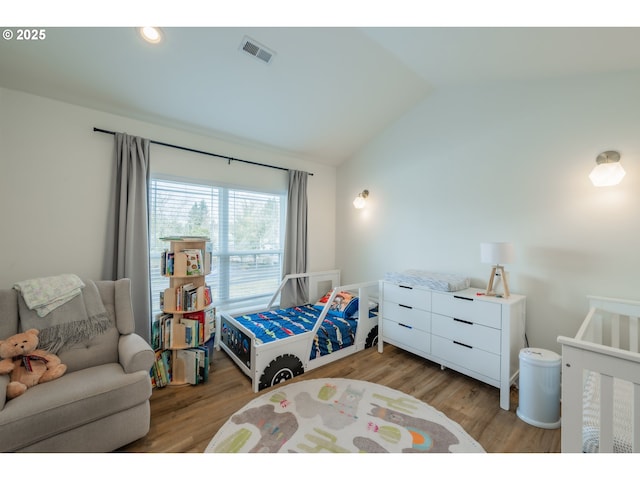 bedroom with lofted ceiling, light wood finished floors, and visible vents