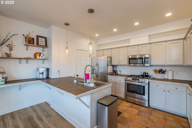 kitchen with a breakfast bar, appliances with stainless steel finishes, tile counters, open shelves, and pendant lighting