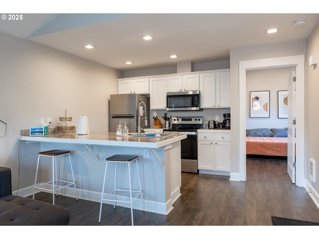 kitchen featuring a breakfast bar area, a peninsula, white cabinetry, light countertops, and appliances with stainless steel finishes