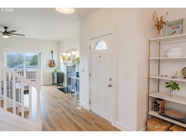 foyer with visible vents, stairway, a ceiling fan, light wood-type flooring, and baseboards