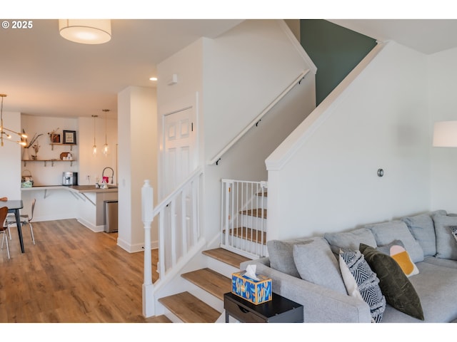 living area featuring recessed lighting, an inviting chandelier, wood finished floors, baseboards, and stairs