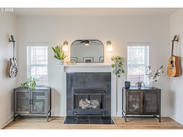 interior space with a tile fireplace, a healthy amount of sunlight, and wood finished floors