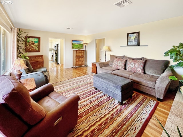 living area featuring light wood-style flooring and visible vents
