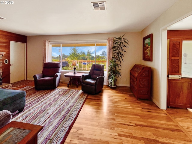 living room featuring baseboards, light wood-style floors, and visible vents