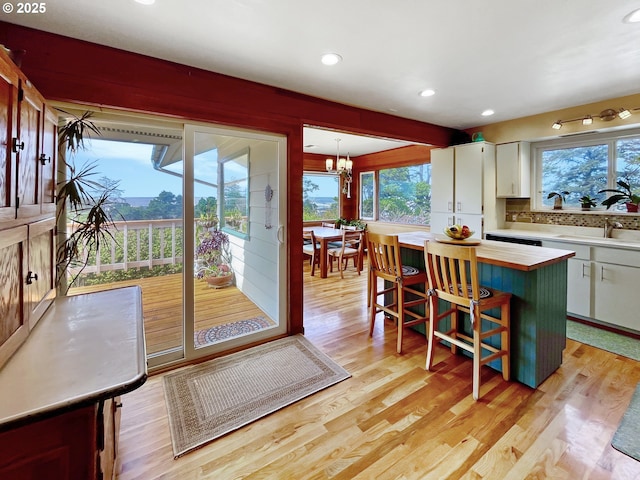 kitchen featuring white cabinetry, wooden counters, light wood-style floors, and a breakfast bar