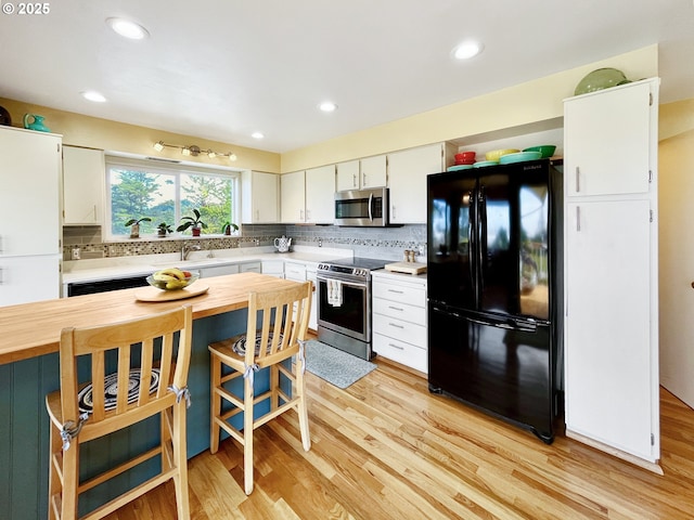 kitchen with tasteful backsplash, wooden counters, light wood-style floors, white cabinets, and appliances with stainless steel finishes